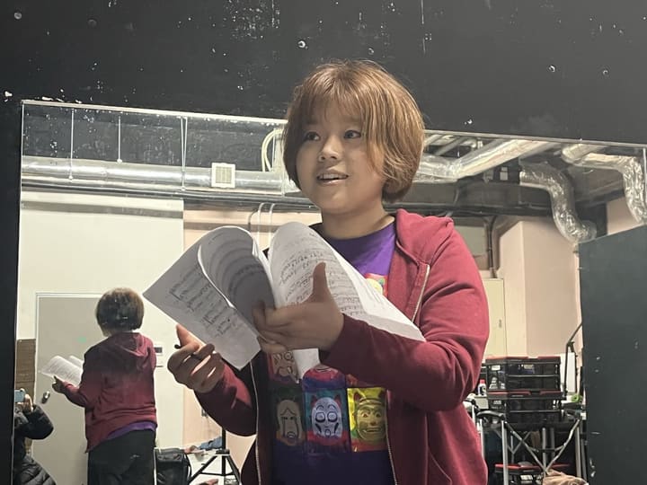 書き込みの入った楽譜を両手に持ち、歌詞を確かめながら歌う団員｜劇団カスタリア 歌唱稽古
