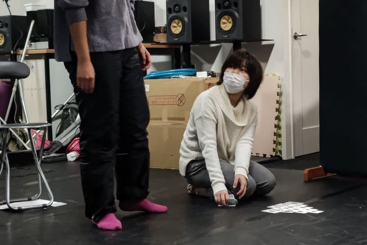 床のカードを拾いながら、立つ相手を見上げて演じる団員｜劇団カスタリア 演技稽古