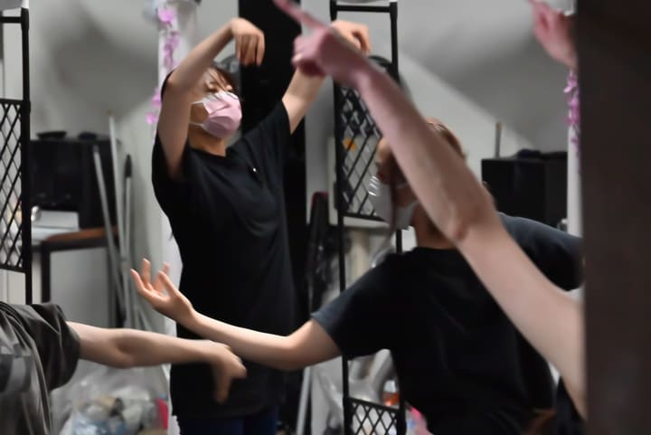 鏡張りの壁の前で腕を頭の上で交差させ、振りを合わせる団員たち｜劇団カスタリア「オーブ」ダンス稽古