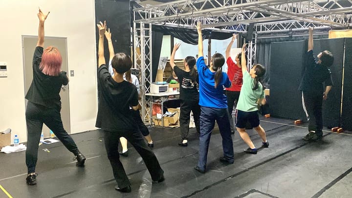 片腕を高く突き上げ、脚を開いて振りをそろえる団員たち｜劇団カスタリア ダンスの振り固め稽古
