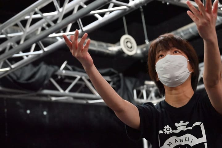 両手を大きく広げて上を見上げる、MANKAIロゴの黒Tシャツの団員｜劇団カスタリア ナンバー稽古