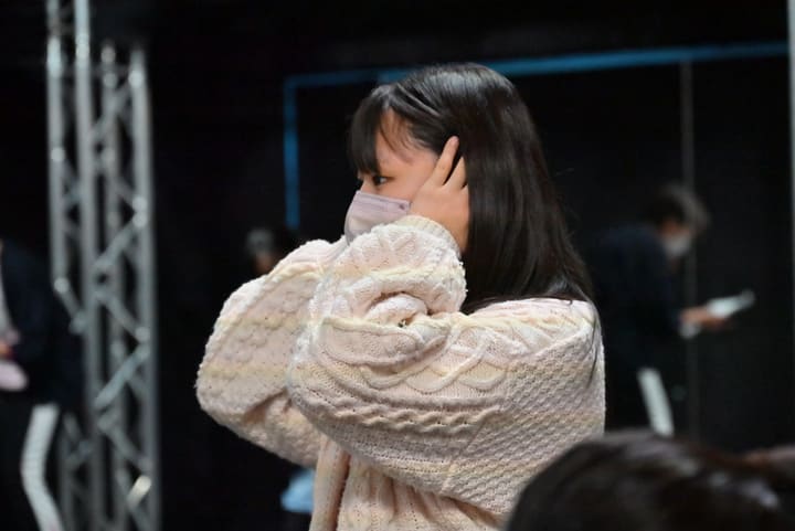 白いニット姿で髪に手をやり、出番を待つ出演者の横顔｜劇団カスタリア 通し稽古