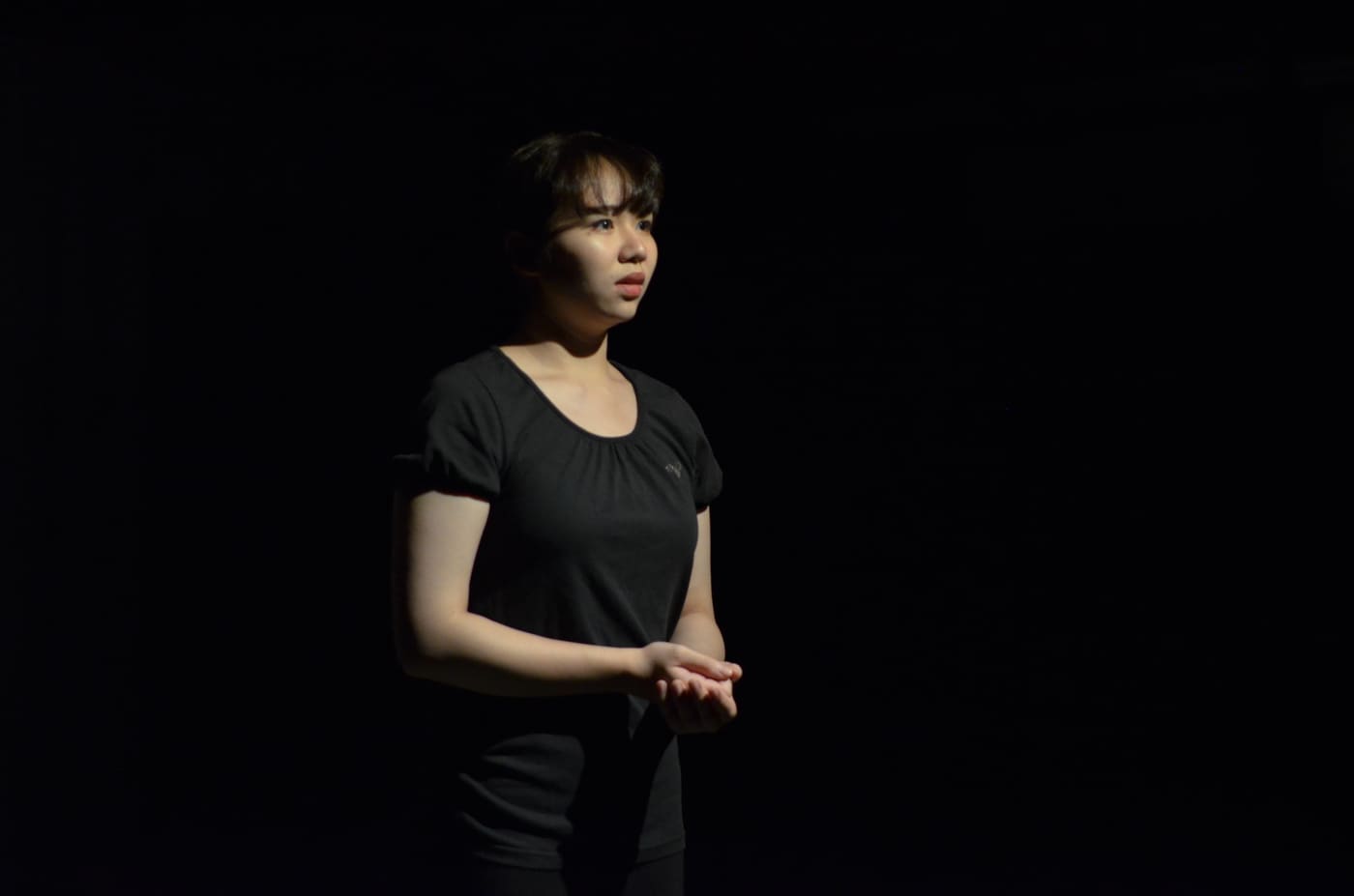 暗転した舞台に一人、手を前で組んで立つ出演者｜劇団カスタリア第3回公演「DAHLIA」本番写真