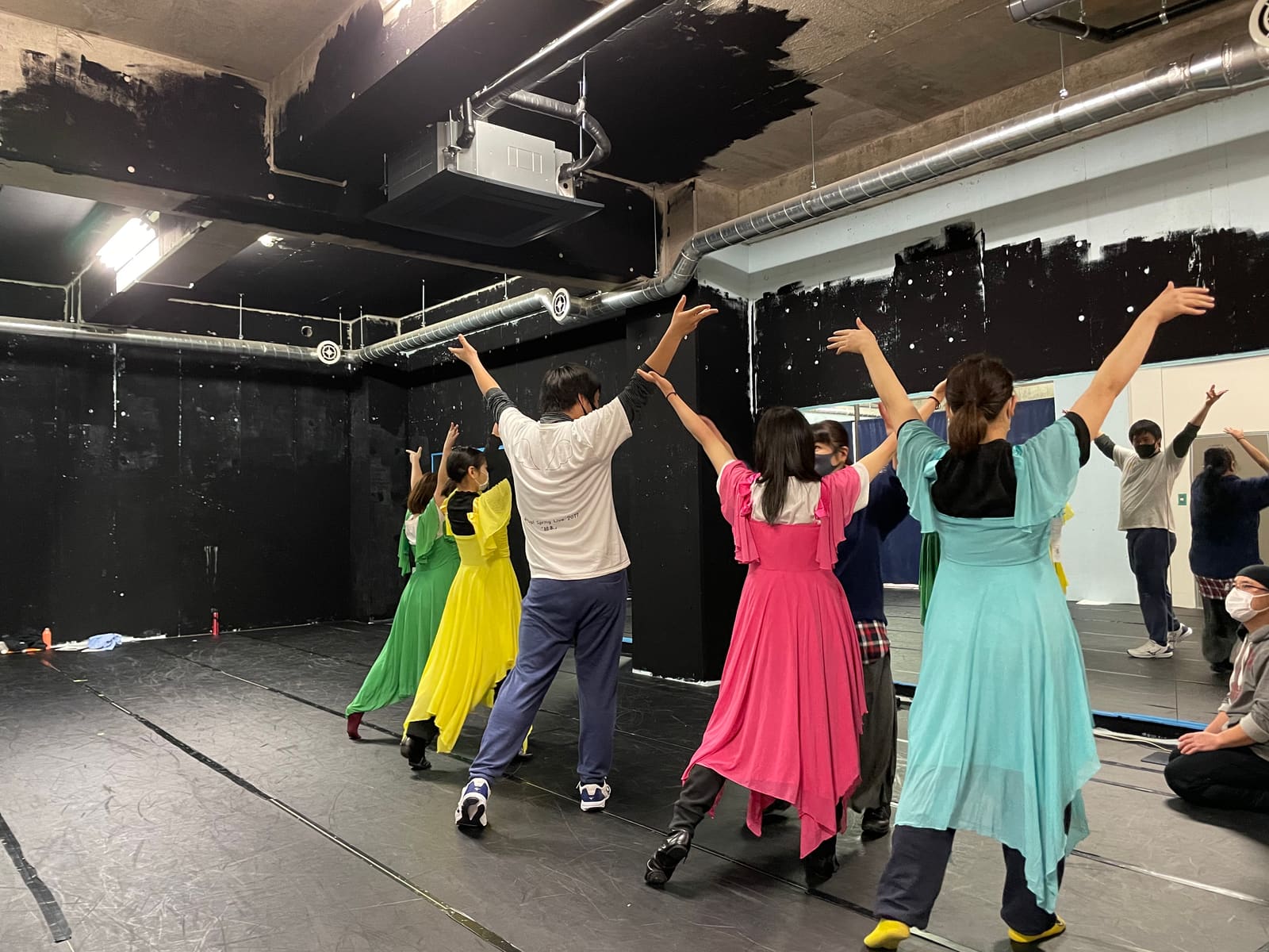 緑や黄、ピンクのロングドレスで両腕を高く上げて踊る団員たち|劇団カスタリア ダンス稽古