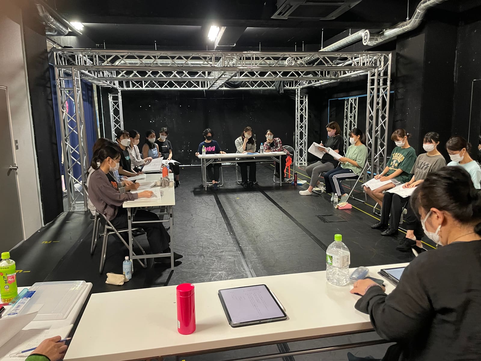 机を四方に囲んで座り、台本を開いて読み合わせる団員たち|劇団カスタリア 本読み稽古