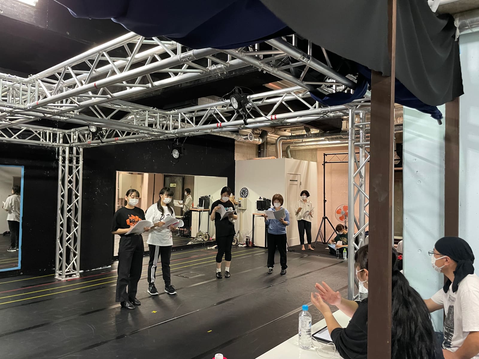 台本を手に並んだ団員へ、机の側から指示が飛ぶ稽古場｜劇団カスタリア 立ち稽古