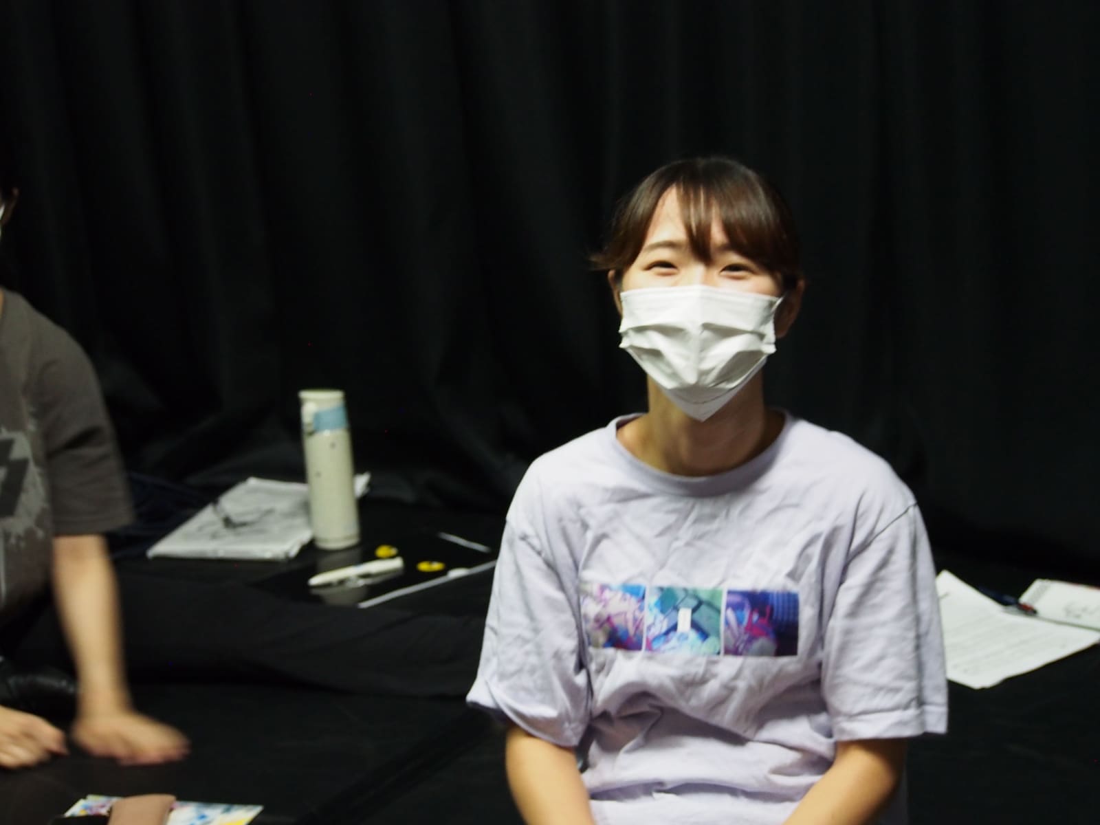 黒い稽古場で腰かけ、笑顔でカメラを見る団員｜劇団カスタリア 稽古オフショット