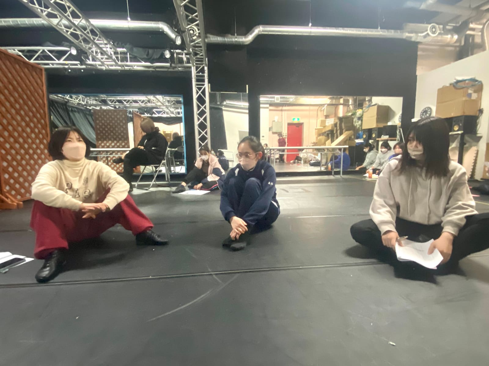 稽古場の床に間隔をあけて座り、演技を見つめる団員3人｜劇団カスタリア 立ち稽古
