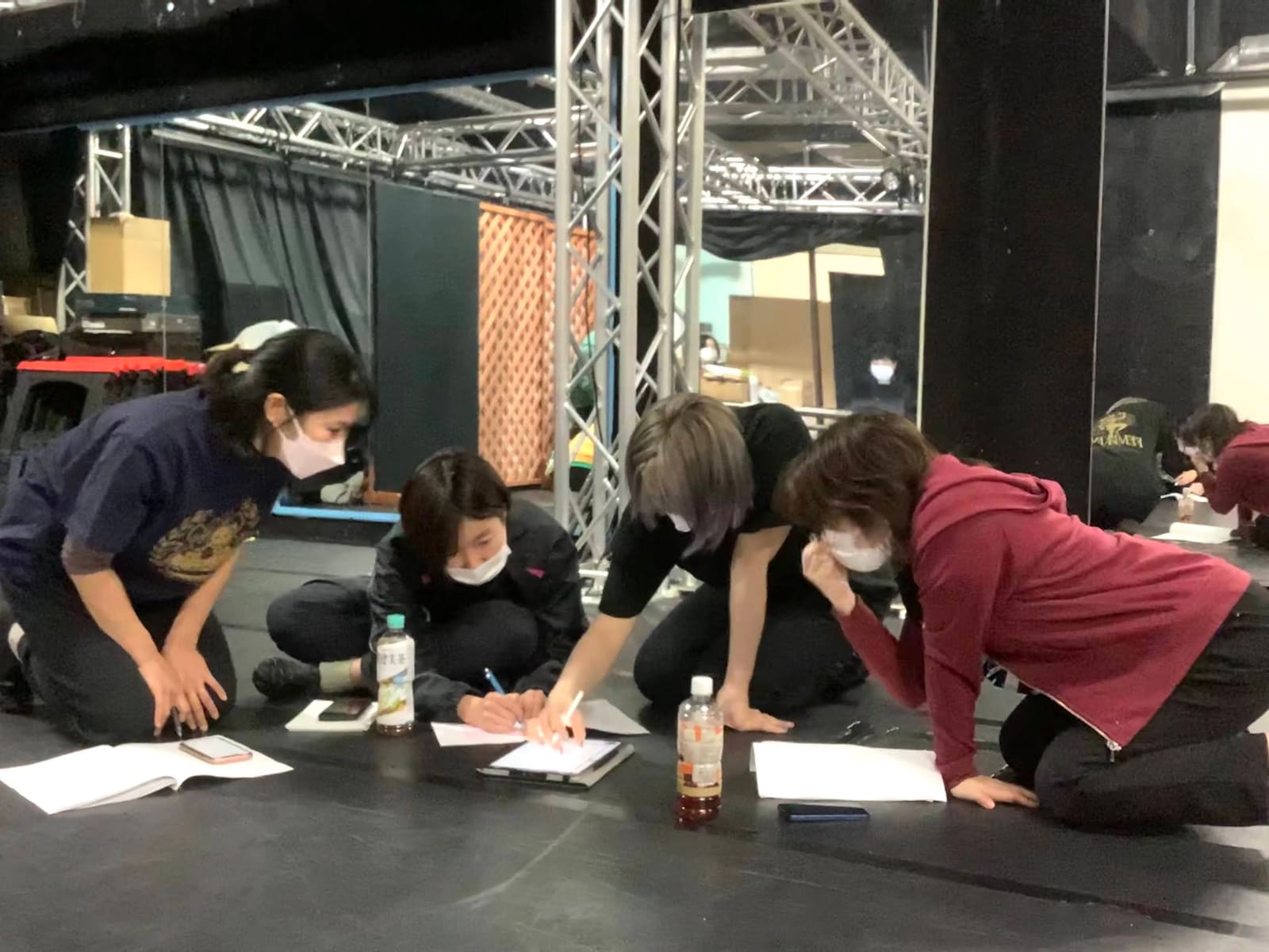 床に広げた紙をのぞき込み、書き込みを加える団員4人｜劇団カスタリア「ルドベキアフェスティバル」本読み