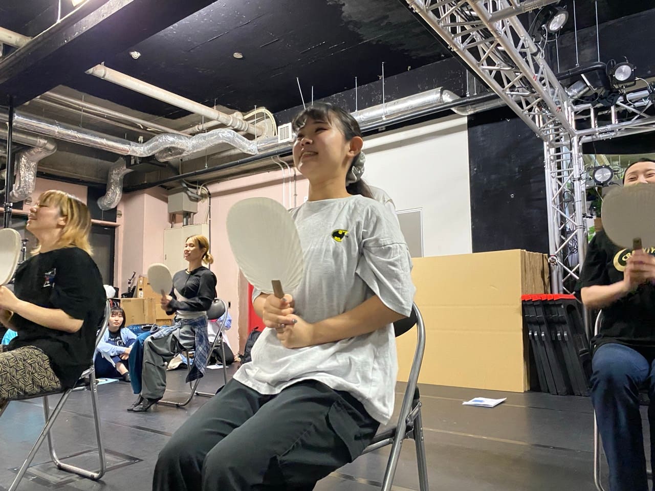 うちわを持って椅子に座り、笑顔でナンバーの振りを合わせる出演者たち｜劇団カスタリア「清子と桃香」振り付け稽古