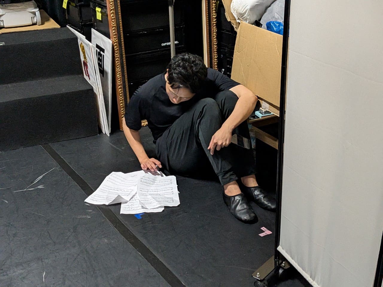 稽古場の隅に座り、床に広げた楽譜を読み込む出演者|劇団カスタリア「清子と桃香」稽古