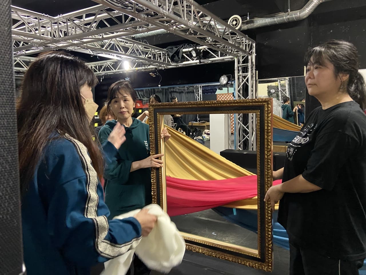 金の額縁に赤と黄の布を通し、絵に見立てる大道具の使い方を確認する出演者たち|劇団カスタリア「清子と桃香」稽古