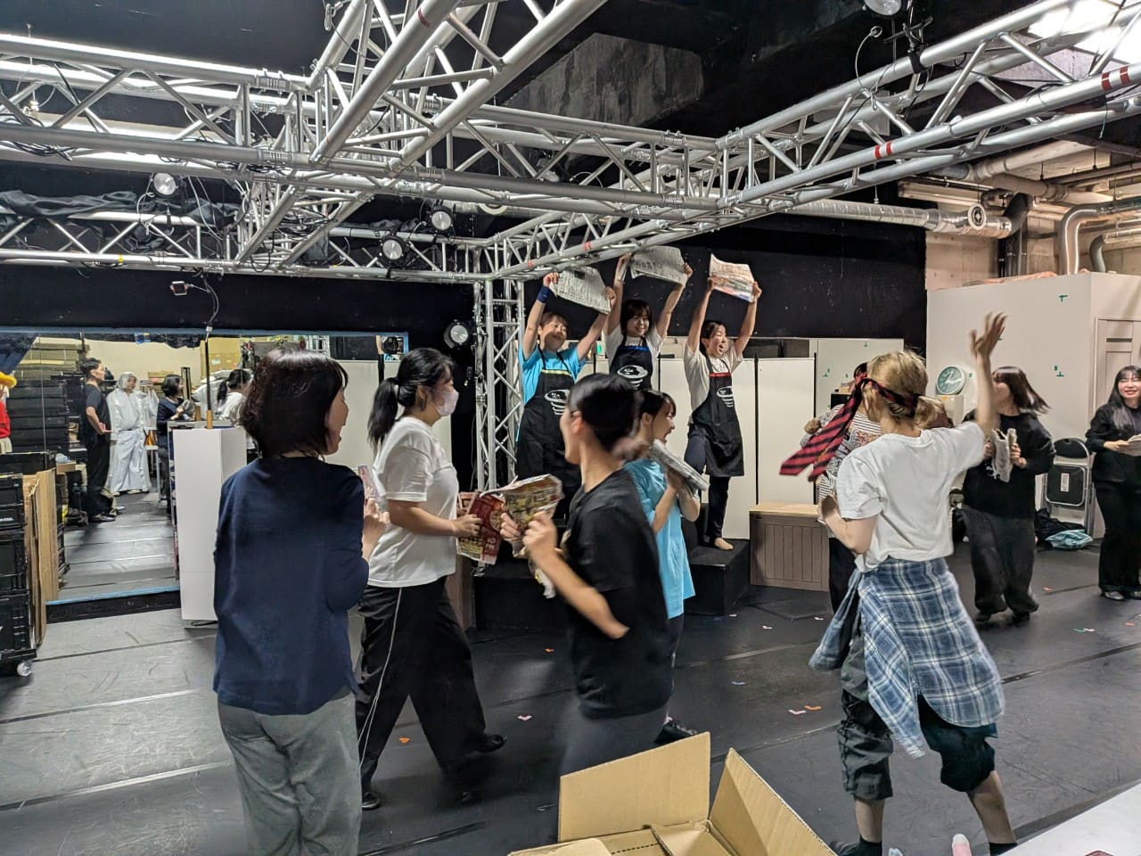 新聞紙を掲げるアルバイト役と、それを囲む出演者たちの場面稽古|劇団カスタリア「清子と桃香」稽古