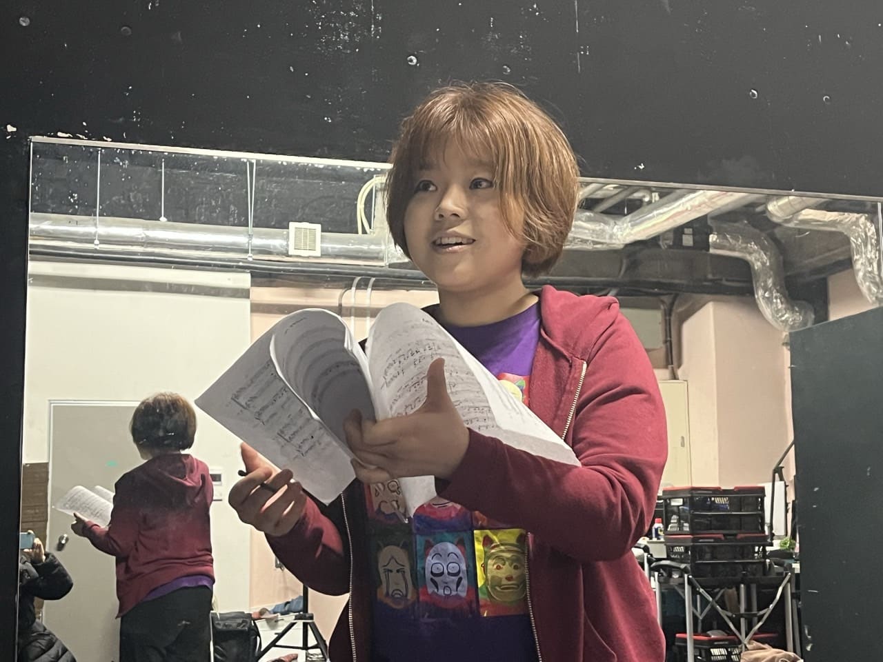 書き込みの入った楽譜を両手に持ち、歌詞を確かめながら歌う団員|劇団カスタリア 歌唱稽古