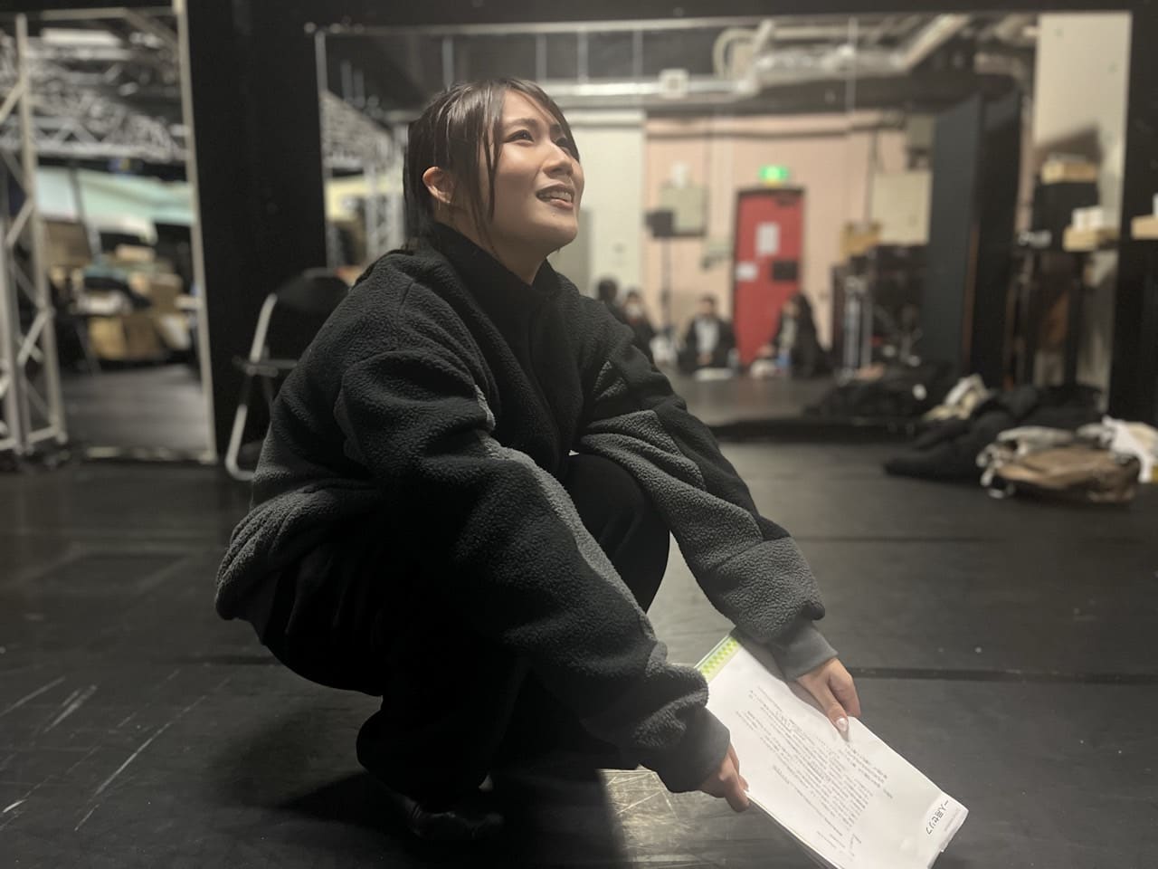 しゃがんだ姿勢で台本を押さえ、視線を上げて演じる団員|劇団カスタリア 演技稽古