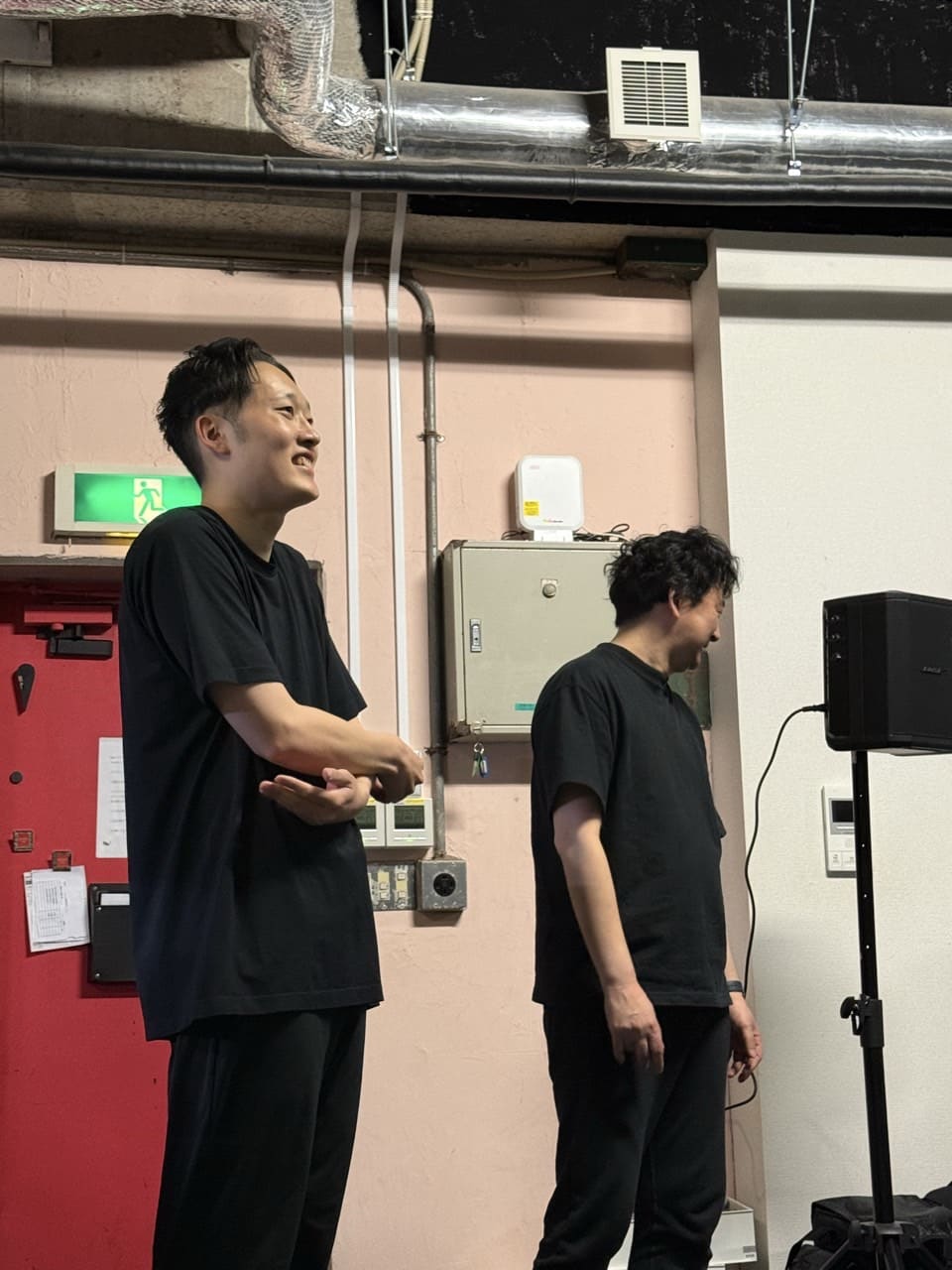 黒シャツで並び、笑顔で稽古の順番を待つ団員2人｜劇団カスタリア「金曜日の食卓」稽古