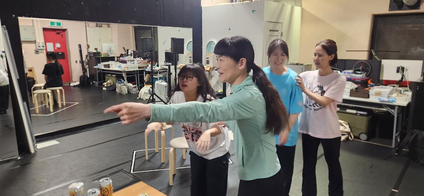 腕を伸ばして動きを示す振付師と、それを見て振付を覚える団員たち｜劇団カスタリア「金曜日の食卓」稽古
